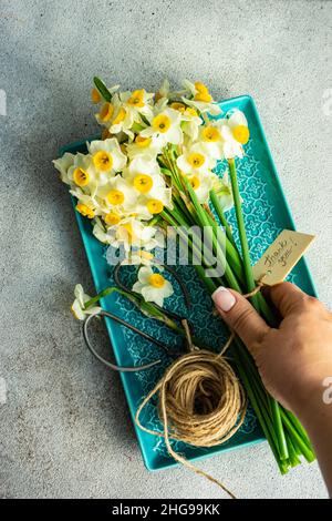 Die Hand der Frau, die nach einem Haufen Narzissen mit einem Dankesschild greift Stockfoto