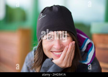 Nahaufnahme einer Frau, die in entspannter Pose isoliert ist, Hand auf Kinn, lächelnd. Stockfoto