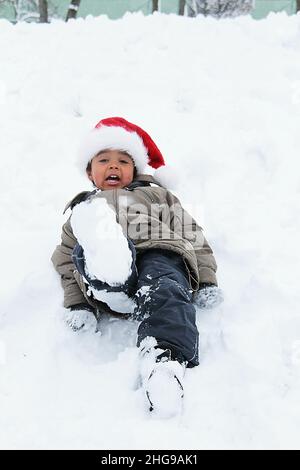 Junge mit Weihnachtsmütze, der im Schnee spielt, Bulgarien Stockfoto