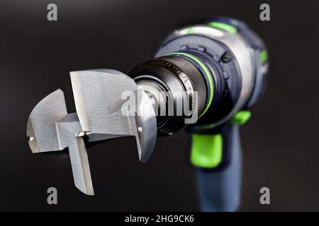 Stahl-Forstner-Bit in Akku-Bohrmaschine auf schwarzem Hintergrund. Professionelles Schneidwerkzeug aus Metall zum Bohren von flachen Löchern in Holz. Bohrmaschine. Stockfoto