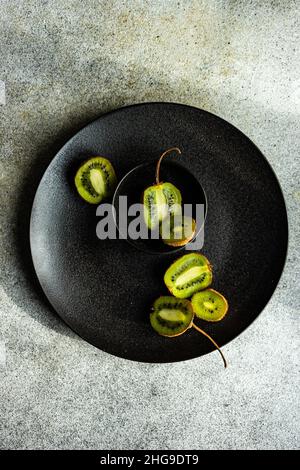 Blick von oben auf frisches Kiwi-Obst auf einem schwarzen Teller Stockfoto