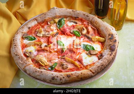 Capricciosa Pizza mit Käse, Speck und Tomaten und Basilikum. Traditionelle italienische Küche. Konzept der gesunden Ernährung für das Menü. Stockfoto