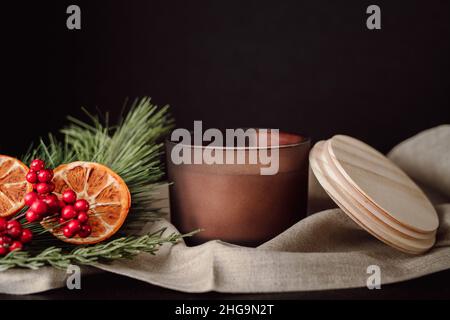 Stillleben Zu Weihnachten. Schokolade Brown Kerze gegen dunklen Hintergrund mit getrockneten Orangen und Cranberries. Moody Spa Stillleben. Stockfoto