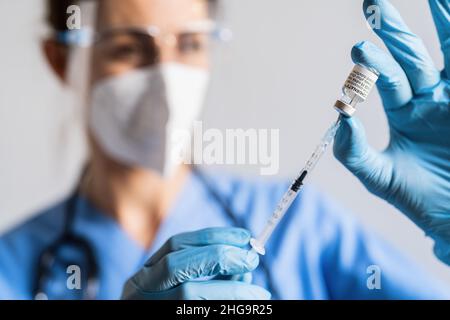 Ein Mitarbeiter im Gesundheitswesen nimmt eine Dosis aus einer Ampulle mit Pfizer-BioNTech-Impfstoff, die im Impfzentrum angeordnet wurde. Stockfoto