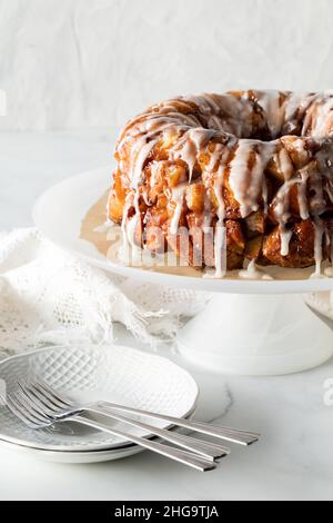 Ein Apfel-Zimt zerlegt Brot auf einem Standfuß mit Geschirr zum Servieren. Stockfoto