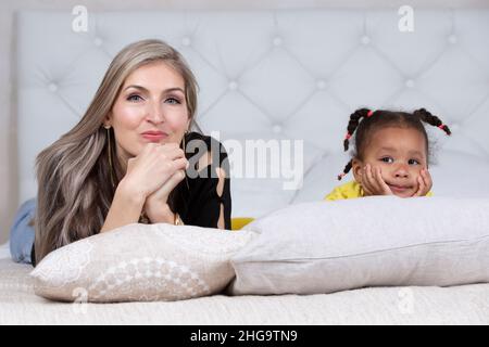 Multiethnische Mutter und Tochter. Fröhliche Mutter mit kleiner Tochter afrikanischer Nationalität. Familie aus verschiedenen Rassen. Stockfoto