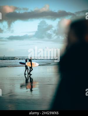 Zwei Surfer am Strand im Morgenlicht Stockfoto