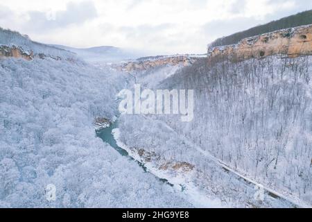 Luftaufnahme des Plateau Lago-Naki Berg verdrehte Straße im Winter und Auto fahren. Epischer, schneeweißer Winter und schneebedeckter Wald. Stockfoto