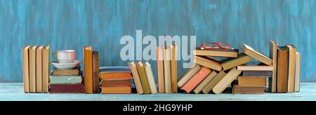 Reihe von Büchern, gebundene Bücher auf Holztisch auf blauem Hintergrund. Zurück zur Schule, Bildung, Lesen, Home Office. Großer, freier Speicherplatz für Panoramafenster Stockfoto