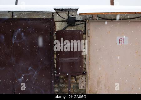 Großer Blechfass, der im Schnee an der Wand hängt Stockfoto