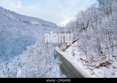 Luftaufnahme des Plateau Lago-Naki Berg verdrehte Straße im Winter und Auto fahren. Epischer, schneeweißer Winter und schneebedeckter Wald. Stockfoto