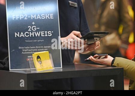 Bayern kippt die 2G-Regel im Handel Archivfoto; Kontrolle der 2G-Regel im Handel in Bayern. Ein Schild am Eingang eines Ladens weist auf die Regel von 2G hin. Einreise nur mit FFP2 Maske und 2g Nachweis, haben Nachweis der Impfung und Ausweis bereit, ein Mitarbeiter überprüft die 2G Regel vor der Einreise - geimpft, erholt. Eintritt nur für geimpfte oder wiederhergestellte Kunden, Personen, Impfpass und Personalausweis bereit. Smartphone, Handy. Â Stockfoto