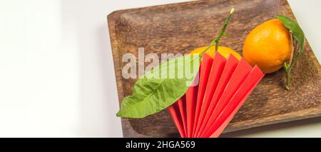 Chinesisches Neujahr, Komposition mit Mandarinen, lustiges Origami aus rotem Papier auf einem dunklen Holzteller auf weißem Hintergrund, Platz für Text auf dem lef Stockfoto