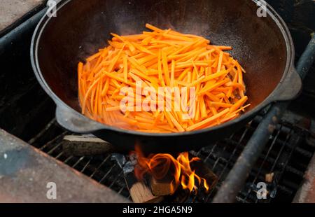 Karotte wird im Kessel auf Feuer gekocht. Schritt für Schritt Kochen von Pilaf. Stockfoto