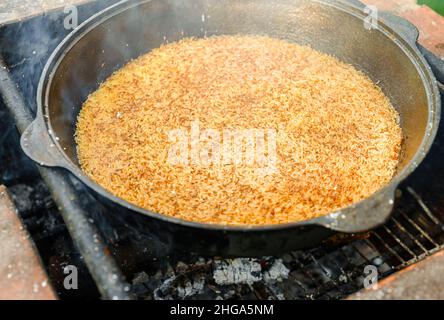 Reis wird im Kessel auf Feuer gekocht. Schritt für Schritt Kochen von Pilaf. Stockfoto