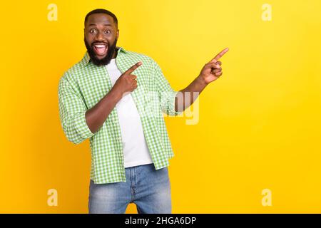 Foto von positiven erstaunt Kerl zeigen zwei Finger leeren Raum Förderung isoliert auf gelbem Hintergrund Stockfoto