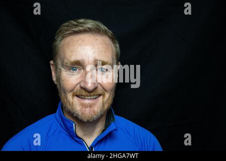 50 etwas männlich, Bart und dunkelblonde Haare tragen blaues Hemd Stockfoto