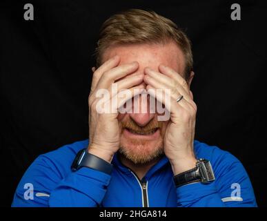 50 etwas männlich, Bart und dunkelblonde Haare tragen blaues Hemd Stockfoto