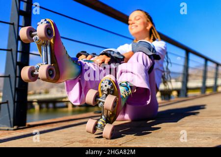 Glückliche Frau mit langen blonden Zöpfen Haare auf dem Rollschuh im Park Strand und Berg Hintergrund Stockfoto