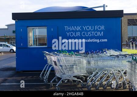 Supermarktwagen, die neben dem Car Wash / Car Valeting Gebäude im Morrisons Car Park, Essex, Großbritannien, abgestapelt wurden Stockfoto