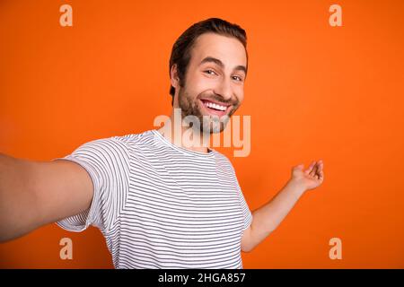 Foto von jungen aufgeregt Kerl Promoter zeigen Arm leeren Raum Influencer isoliert über orangen Hintergrund Stockfoto