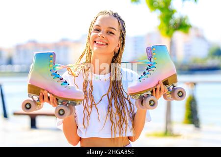 Glückliche Frau mit langen blonden Zöpfen Haare whilen ihre Rollschuh im Park Strand und Berg Hintergrund Stockfoto