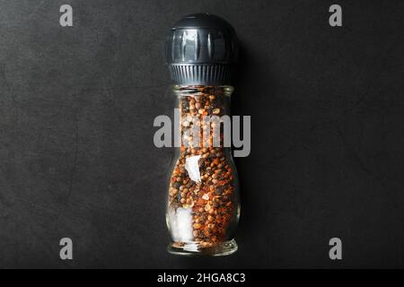 Pfefferkörner Kreuzkümmel und Salz in einer transparenten Mühle auf schwarzem Hintergrund Stockfoto