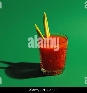 Glas mit Cocktail Bloody mary isoliert auf hellgrünem Neon-Hintergrund. Konzept des Geschmacks, alkoholische Getränke Stockfoto