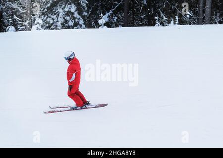 Snowboarder im roten Skianzug steigt auf den Lift bergauf. Skisport im Winter. Urlaub in den Bergen im Skigebiet. Stockfoto