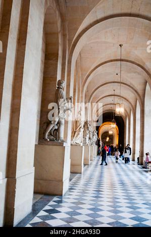 Gewölbte Decke und karierter Marmorboden einer mit Statuen gesäumten Halle im königlichen Palast von Versailles in der Nähe von Paris in Frankreich. Stockfoto