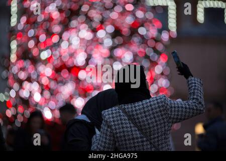 In Covent Garden, im Zentrum von London, fotografieren Menschen am Nachrichtenabend vor festlichen Lichtern. Stockfoto