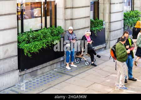 London, Großbritannien - 22. Juni 2018: Blick auf die Straße in London mit einem Mauergebäude und offenen Menschen, die Fußgänger an der Bushaltestelle auf dem Bürgersteig warten Stockfoto