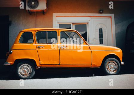 Auf den Straßen Montenegros steht ein helles altes, gelbes Auto. Bild Stockfoto