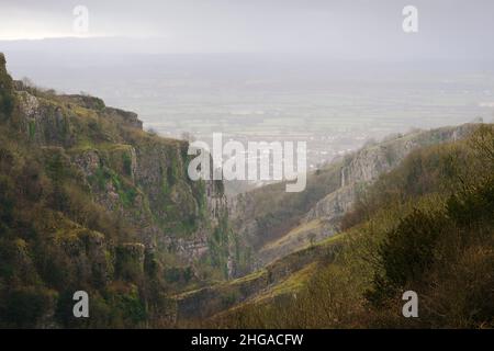 Die Kalksteinfelsen der Cheddar Gorge in den Mendip Hills mit dem Dorf Cheddar und Somerset liegen im Hintergrund während eines Regensturms im Winter, Somerset, England. Stockfoto