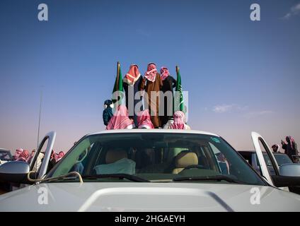 Saudische Männer folgen Kamelen mit ihren Autos während des King Abdul Aziz Camel Festivals, Provinz Riyadh, Rimah, Saudi-Arabien Stockfoto