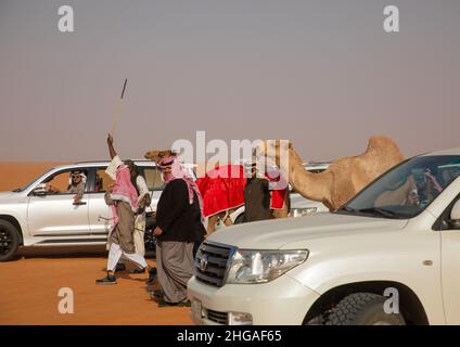 Saudische Männer folgen Kamelen mit ihren Autos während des King Abdul Aziz Camel Festivals, Provinz Riyadh, Rimah, Saudi-Arabien Stockfoto