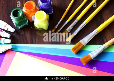 Kunst- und Handwerksausrüstungen, Kunstwerke, Farbpapier, Farbtupfer und Bürste auf einem Tisch, Schülerarbeit in der Schule Stockfoto