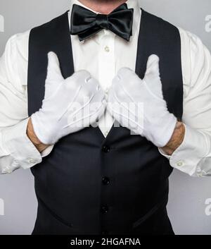 Porträt eines Butlers oder Kellers in schwarzer Weste und weißen Handschuhen, die selbstbewusst stehen. Dienstleistungsbranche und professionelle Gastgewerbe. Stockfoto