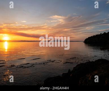 WA21153-00...WASHINGTON - der Blick über die Haro Strait mit Sonnenuntergang hinter Vancouver Island vom Lime Kiln State Park auf San Juan Island. Stockfoto