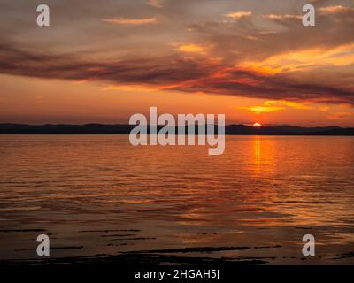 WA21155-00...WASHINGTON - Ein farbenfroher Sonnenuntergang, der durch den Rauch eines Waldfeuers auf Vancouver Island vom Lime Kiln State Park auf San Juan Island aus betrachtet wird. Stockfoto