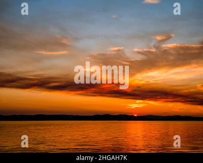 WA21156-00...WASHINGTON - Ein farbenfroher Sonnenuntergang, der durch den Rauch eines Waldfeuers auf Vancouver Island vom Lime Kiln State Park auf San Juan Island aus betrachtet wird. Stockfoto