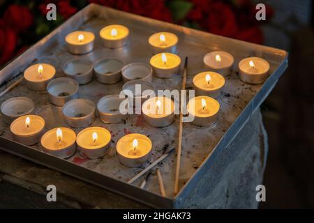 Brennende Gebetskerzen in einer katholischen Kirche. Beleuchtete Teelichter. Selektiver Fokus. Stockfoto