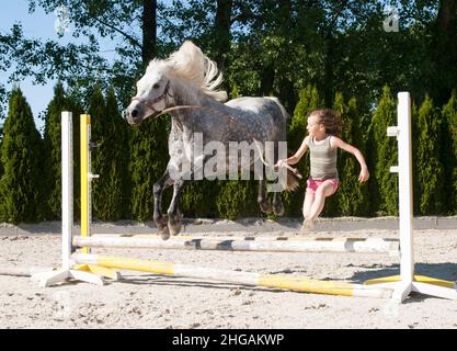 Mädchen springen mit Pony über Hürde Stockfoto