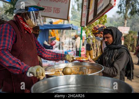 Ghaziabad, Indien. 19th Januar 2022. Ein Arbeiter, der einen Gesichtsschutz trug, sah, wie er in einem subventionierten Lebensmittelzentrum in Vashundhara Lebensmittel servierte.Ein Lebensmittelzentrum, das von Tirthankar Mahavir Manav Seva Trust (einem gemeinnützigen Verein, der für soziale Zwecke in Indien arbeitet) betrieben wird, berechnet 5 indische Rupien pro Teller mit Lebensmitteln, Die meisten Nutznießer aus dem ärmsten Teil der Gesellschaft, die stark von der Pandemie und der Sperrung betroffen waren, kommen immer und nehmen ihr Nahrung. Kredit: SOPA Images Limited/Alamy Live Nachrichten Stockfoto