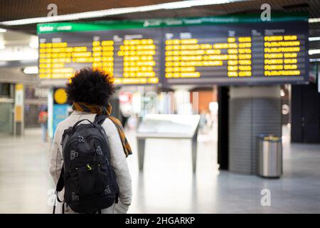 Junge männliche Reisende, die die Abflugs- und Ankunftskonsole am Flughafen oder Bahnhof betrachten. Platz für Text. Stockfoto