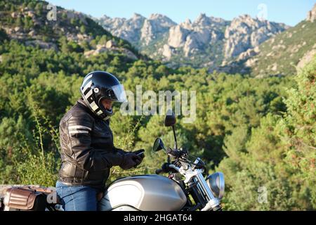 Motorradfahrer mit dem Handy in der Natur Stockfoto