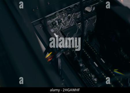 Ein Mann zu Hause sammelt, zerlegt einen Computer. Hände eines Mannes halten Drähte, verbindet Drähte. Sammeln eines Computers für Profis, ein Gaming-Computer Stockfoto