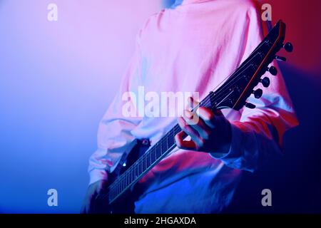 Leidenschaftlicher Gitarrist Musik Konzept Foto. E-Gitarre spielt Closeup Foto. Rockmusik-Band. Neonlicht-Club Stockfoto