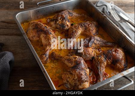 Gebratene Hähnchenschenkel in einer köstlichen Harissa-Sahnesauce isoliert auf einem Holztisch. Ansicht von oben Stockfoto