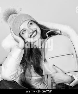 Perfektes Lächeln. Grippe und kalte Jahreszeit. Ledertasche Mode. Warme Winterkleidung. Shopping. Frohe Winterferien. Mädchen in Puffmantel. Kunstpelzmode Stockfoto